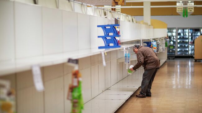 Мужчина берет с пустой полки пачку туалетной бумаги в супермаркете в Род-Айленд.