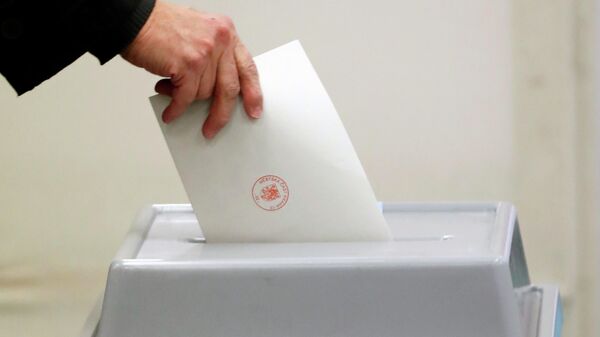 Человек опускает бюллетень в избирательную урну в Чехии