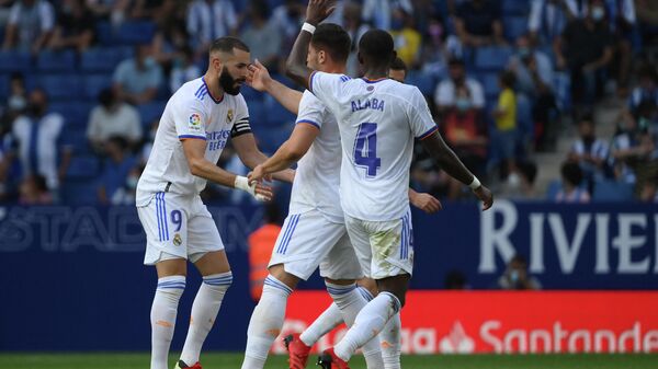 Real Madrid's French forward Karim Benzema (L) celebrates with teammates after scoring a goal during the Spanish League football match between RCD Espanyol and Real Madrid CF at the RCDE Stadium in Cornella de Llobregat on October 3, 2021. (Photo by LLUIS GENE / AFP)