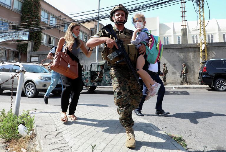 Военнослужащий помогает семье уйти с места митинга