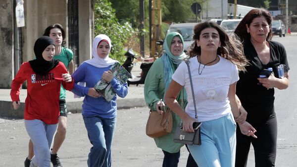 Мирные жители спасаются бегством во время столкновений в районе Тайунех, в южном пригороде столицы Бейрута, после демонстрации сторонников Хезболлы и движения Амаль.