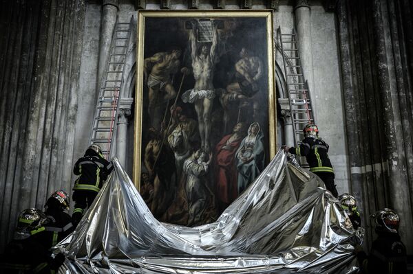 Французские пожарные закрывают картину огнеупорным одеялом во время противопожарных учений в соборе Сент-Андре в Бордо