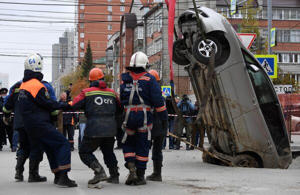 Спасатели муниципальной аварийно-спасательной службы Новосибирска извлекают автомобиль, упавший в провалившийся грунт теплотрассы в Новосибирске