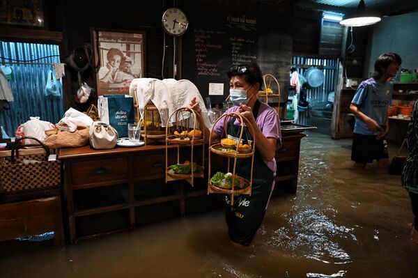 Официант подает десерты в затопленном ресторане Chaopraya Antique Café в Таиланде