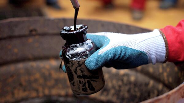 Рабочий собирает образец сырой нефти на нефтяной скважине 
