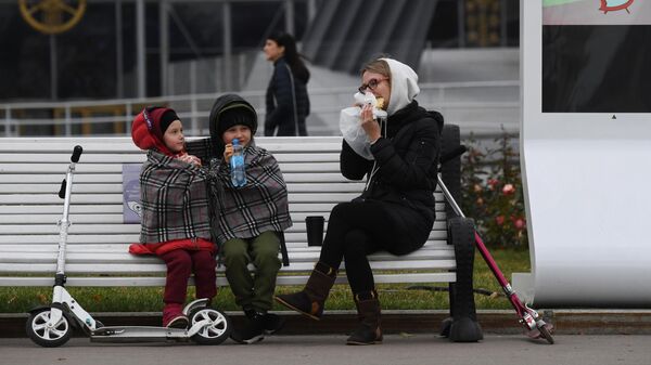 Женщина с детьми отдыхают на скамейке в перерыве прогулки по ВДНХ