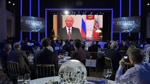 Участники церемонии вручения премии Русского географического общества в Москве смотрят обращение президента РФ Владимира Путина