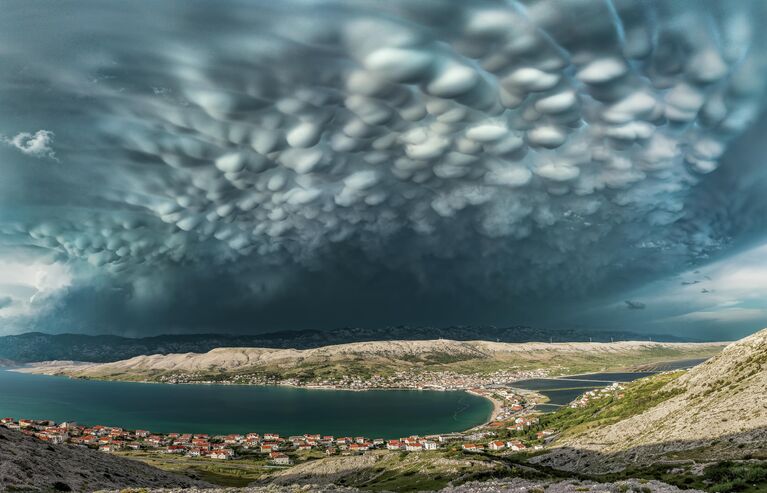 Работа фотографа Danijel Palčić Beautiful Mammatus Clouds above Pag Town, финалист фотоконкурса Weather Photographer of the Year 2021