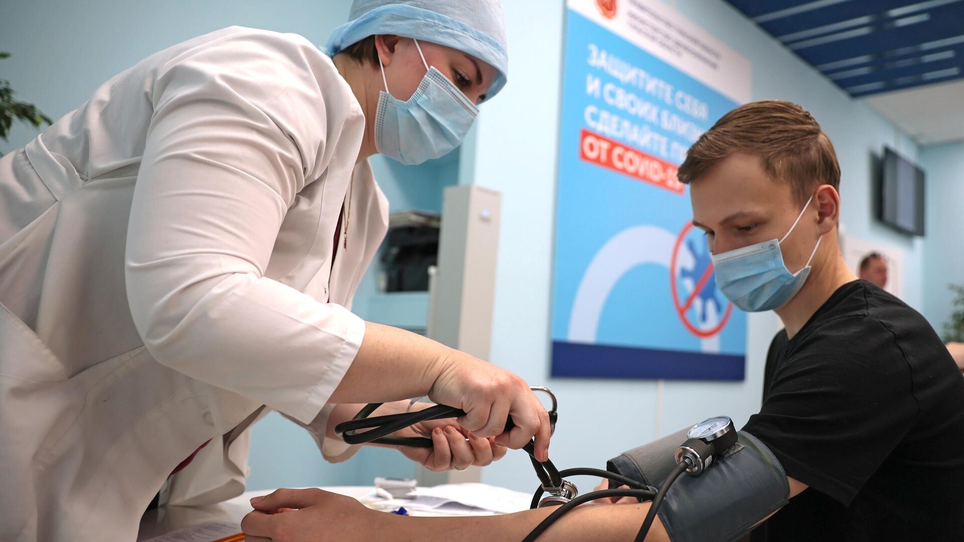 Медицинский работник измеряет давление молодому человеку перед вакцинацией - РИА Новости, 1920, 22.10.2021