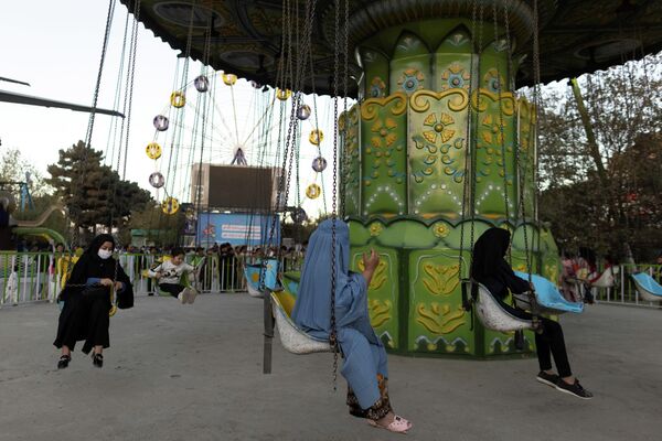 Женщины в бурках катаются на аттракционах в Кабуле, Афганистан 