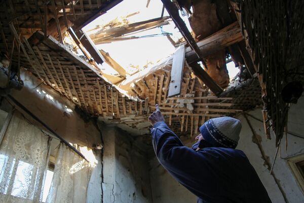 42-летний житель Донецка демонстрирует состояние своего дома на улице Дружбы, в крышу которого попал снаряд