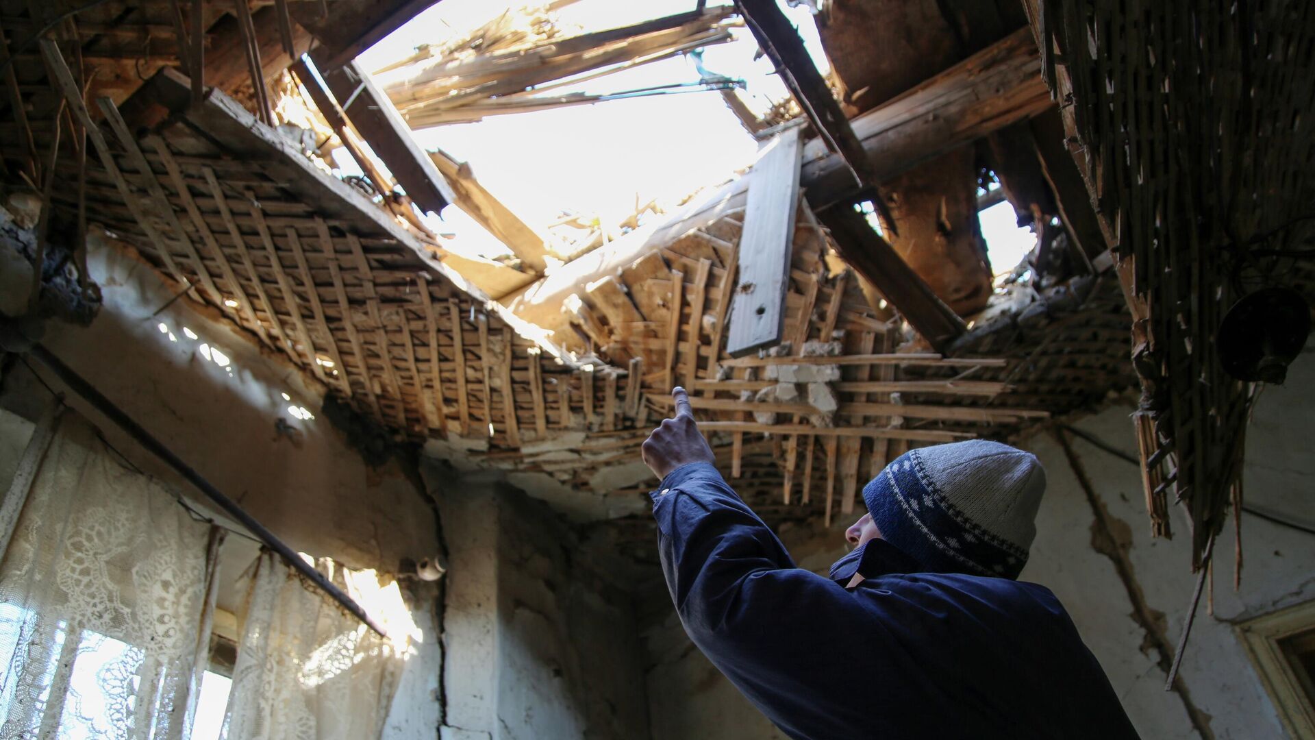 42-летний житель Донецка демонстрирует состояние своего дома на улице Дружбы, в крышу которого попал снаряд - РИА Новости, 1920, 29.10.2021
