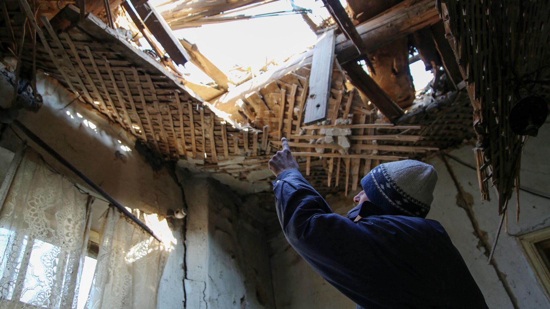 42-летний житель Донецка демонстрирует состояние своего дома на улице Дружбы, в крышу которого попал снаряд - РИА Новости, 1920, 01.01.2022