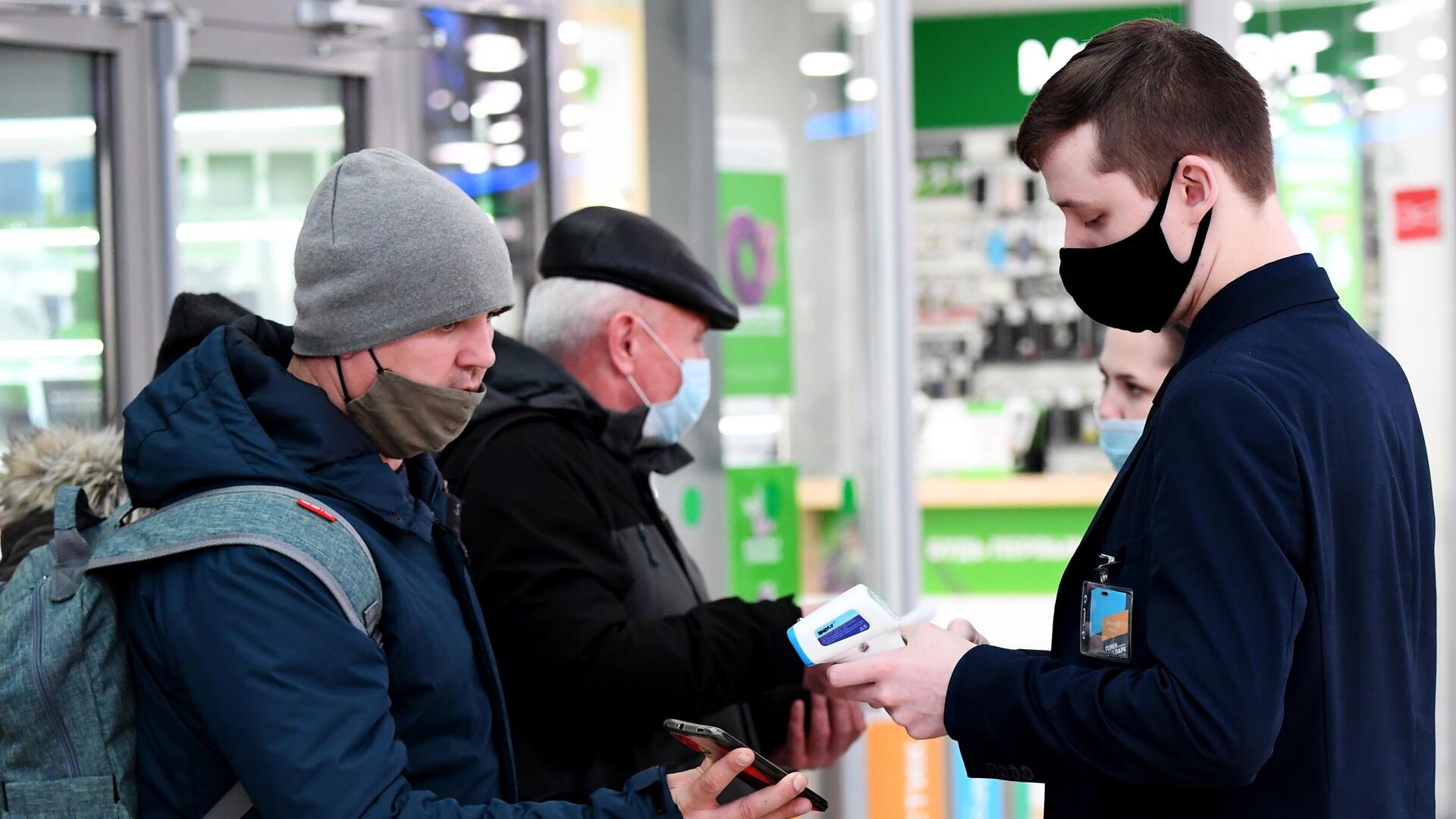 Сотрудник службы безопасности проверяет наличие у посетителей QR-кодов на входе в торговый центр - РИА Новости, 1920, 25.10.2021