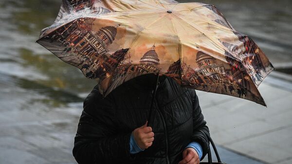 Женщина идет под зонтом во время дождя