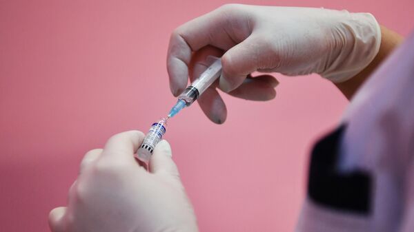 Медицинская сестра набирает вакцину в шприц в пункте вакцинации против COVID-19