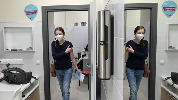 Женщина выходит из кабинета после вакцинации от COVID-19 в торгово-развлекательном центре Columbus в Москве