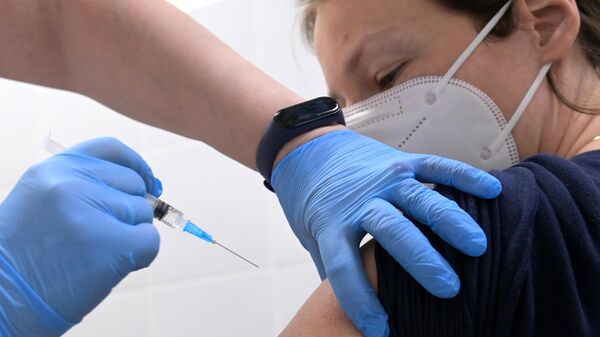 Медицинский работник делает женщине прививку от COVID-19 в торгово-развлекательном центре Columbus в Москве