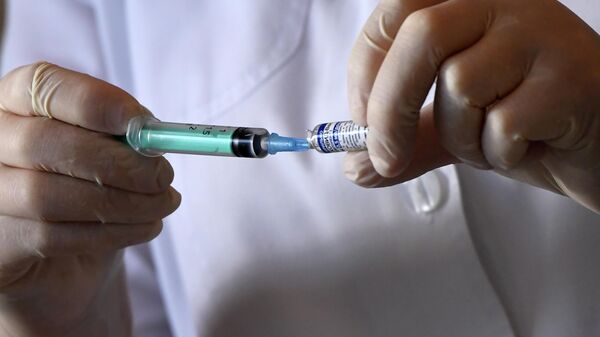 Медицинский работник набирает вакцину Гам-Ковид-Вак (Спутник V) от Covid-19 в шприц в пункте вакцинации у торгово-развлекательного центра МЕГА в Казани