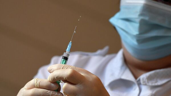 Медицинский работник набирает вакцину 