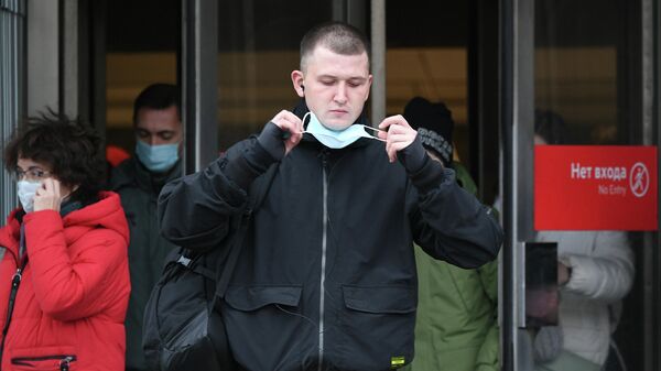 Молодой человек в медицинской маске выходит из станции метро Маяковская Московского метрополитена