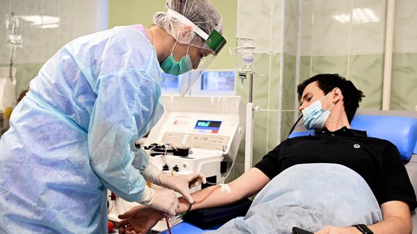 Сотрудница больницы устанавливает катетер для забора плазмы пациенту