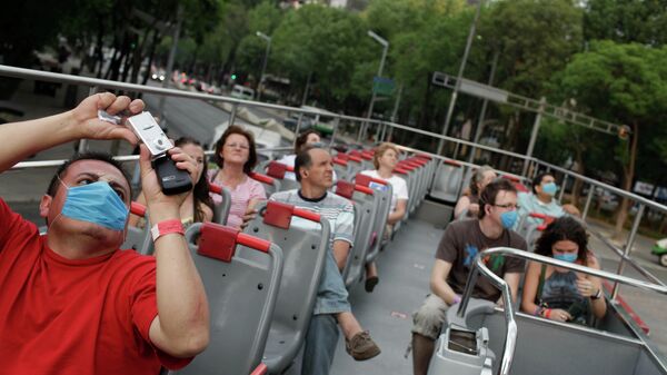Туристы, некоторые в защитных масках, едут в двухэтажном автобусе в Мехико