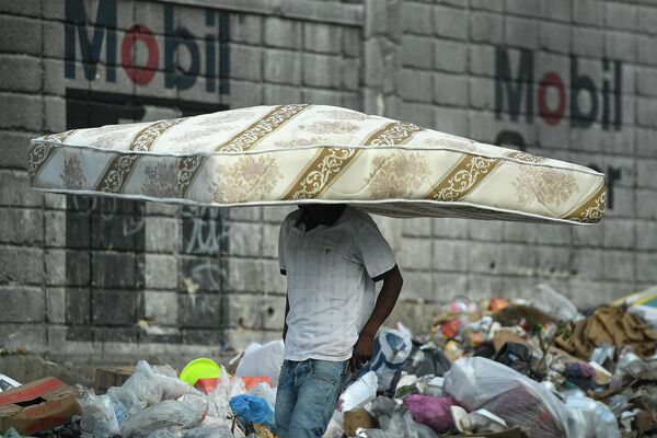 Мужчина несет матрас на голове в Порт-о-Пренсе, Гаити