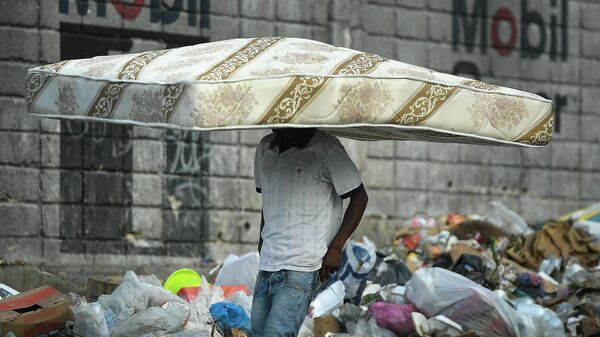 Мужчина несет матрас на голове в Порт-о-Пренсе, Гаити