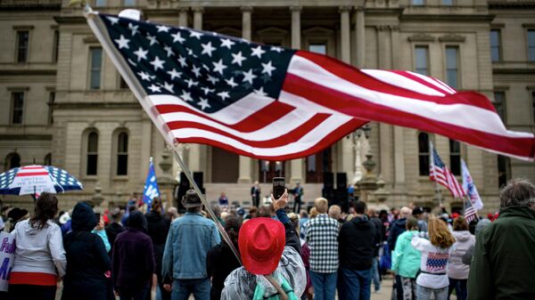 Женщина машет флагом США у Капитолия штата Мичиган в Лансинге