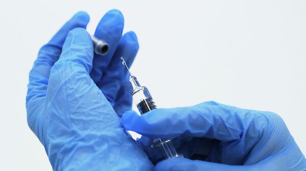 Медик готовит шприц с вакциной против гриппа 360
