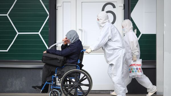 Медицинские сотрудники везут пациента в кресле-каталке в госпитале Минобороны РФ в Волгограде
