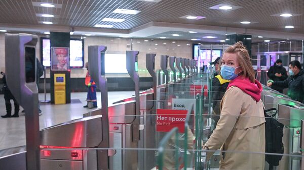 Пассажиры в защитных масках проходят турникеты на станции метро