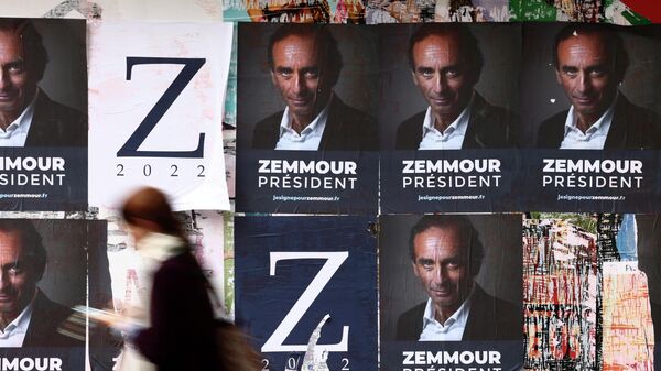 Женщина проходит мимо постеров с изображением Эрика Земмура в Париже 