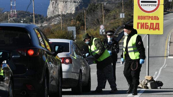 Сотрудники правоохранительных органов и дружинники проверяют наличие QR-кодов у граждан на блокпосту на въезде в Севастополь