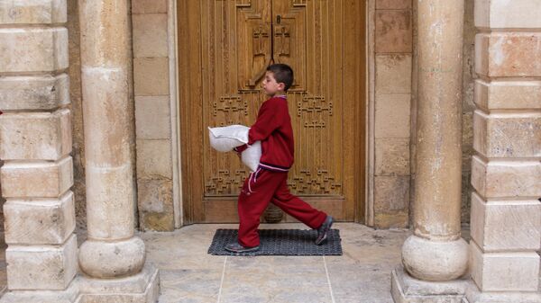 Мальчик с мешком гуманитарной помощи в Храме Святой Марии армянской апостольской церкви в Латакии