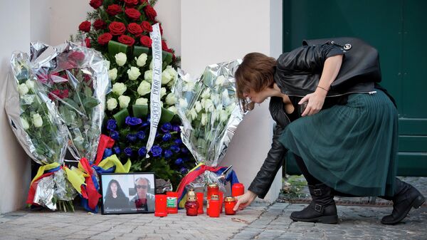Журналистка ставит свечу рядом с фотографиями французских журналистов, убитых в Мали. Бухарест, Румыния