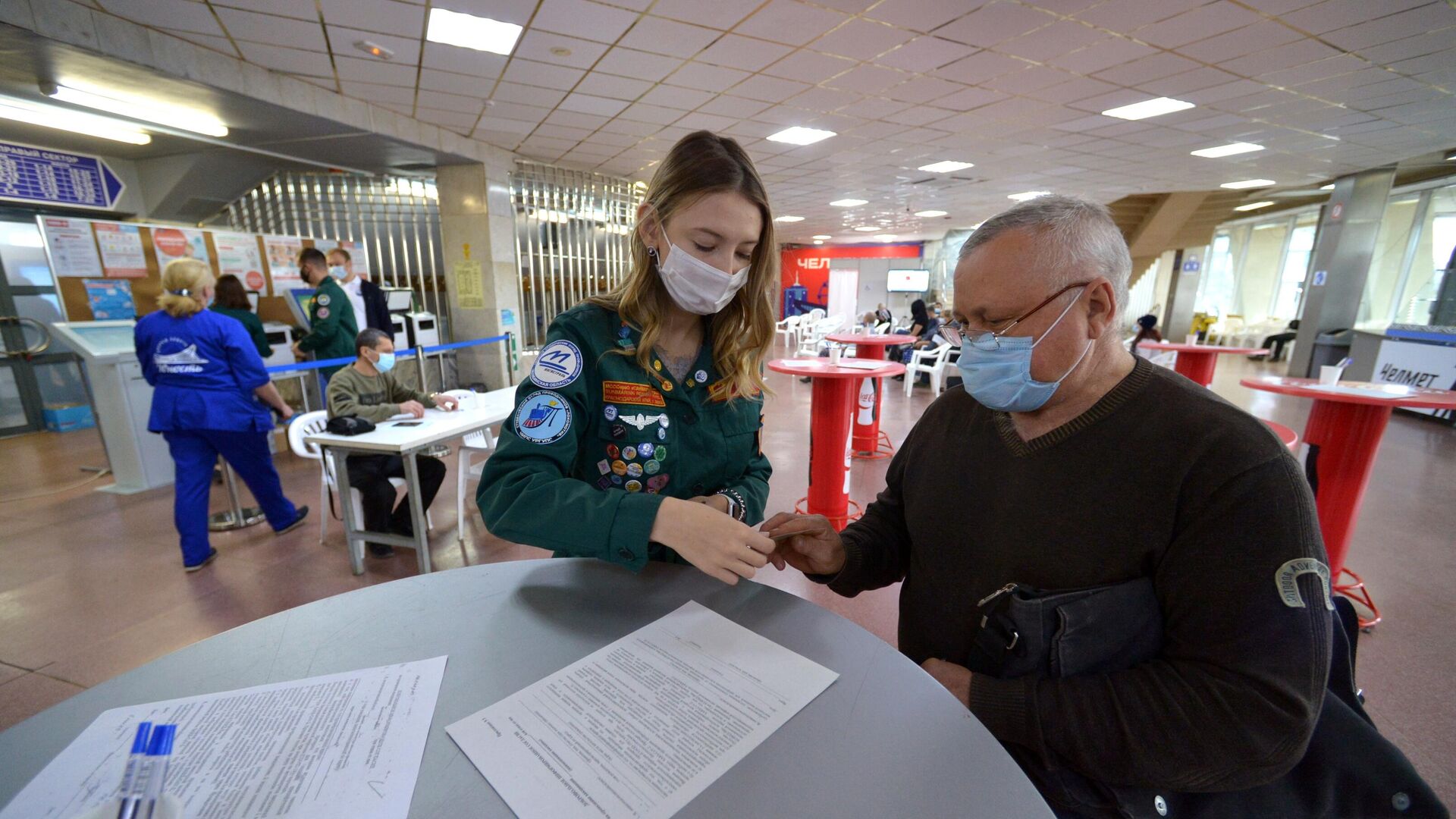 Волонтер помогает заполнить документы посетителю самого крупного на Южном Урале центра вакцинации от COVID-19, открытом во дворце спорта Юность в Челябинске - РИА Новости, 1920, 11.11.2021