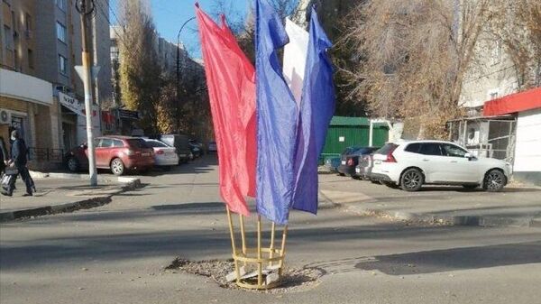 Стойка с флагами в центре ямы на дороге в Саратове. Фото из соцсетей