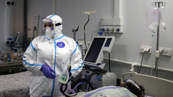 Медицинский работник и пациент в реанимационном отделении COVID-госпиталя