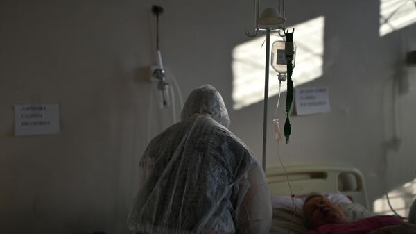 Медик у койки пациента в палате ковидного отделения Тарской районной больницы в Омской области