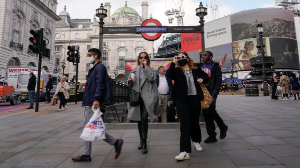 Люди в масках возле метро Piccadilly Circus в Лондоне