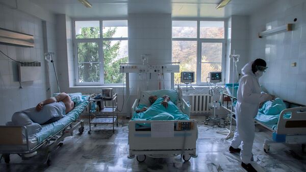 Медицинский работник и пациенты в реанимационном отделении COVID-госпиталя