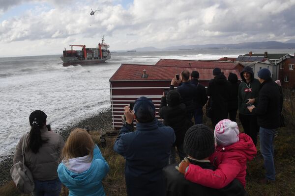 Местные жители наблюдают за эвакуацией экипажа контейнеровоза Rise Shine, севшего на мель в районе мыса Козино у берегов Находки