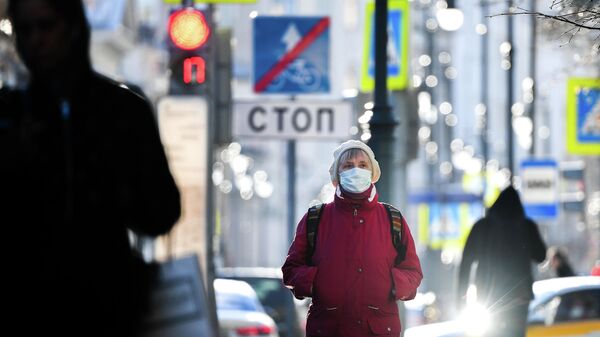 Женщина в маске идет по улице в Москве