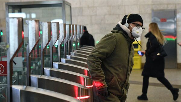 Молодой человек в защитной маске проходит через турникет на станции Цветной бульвар Московского метрополитена