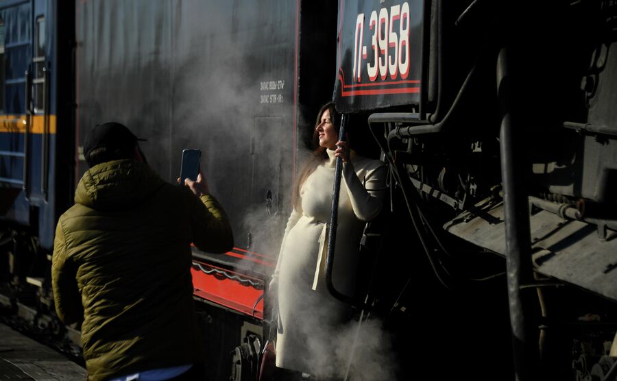 Туристы фотографируются на фоне ретропоезда Рускеальский экспресс, курсирующий по маршруту Сортавала - Горный парк Рускеала - Сортавала, на железнодорожном вокзале Сортавалы