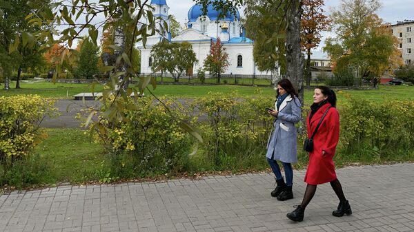 Девушки идут по Карельской улице мимо храма Николая Чудотворца в Сортавале