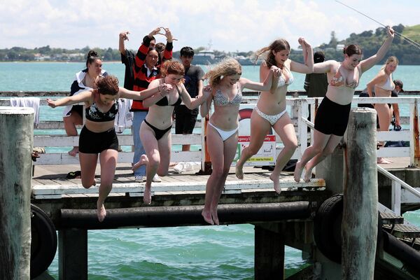 Девушки прыгают с причала в Окленде, Новая Зеландия 
