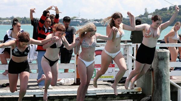Девушки прыгают с причала в Окленде, Новая Зеландия 